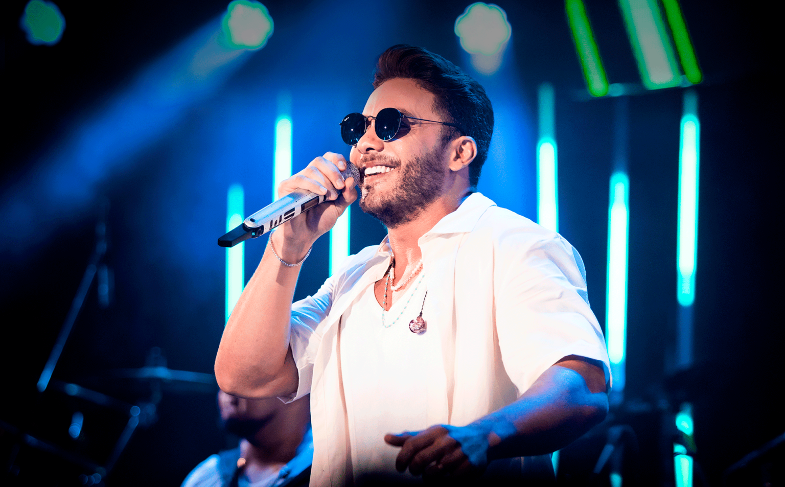 Cantor Wesley Safadão sorrindo com microfone na mão.