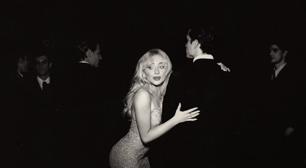 Sabrina Carpenter em um vestido de festa elegante, dançando com um homem em meio a outras figuras em um ambiente escuro. Capa alternativa do álbum Man’s Best Friend.